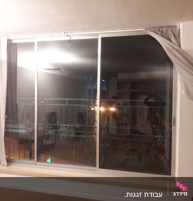 חלון זכוכית גדול עם וילונות בצדדים